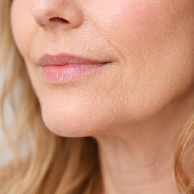 Close-up of a woman's face with blonde hair and pink lipstick.